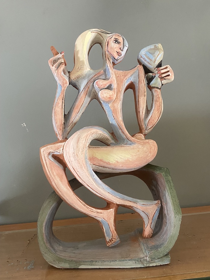 Mujer sentada con un cigarro en una mano y una copa en la otra